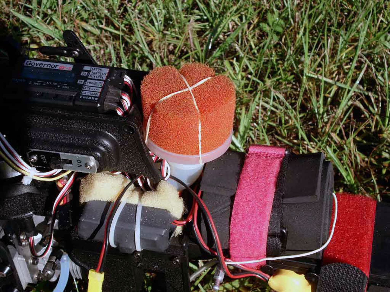 Air filter assembly installed on a Pantera P6 model helicopter with the red foam element secured with a twisted rubber band